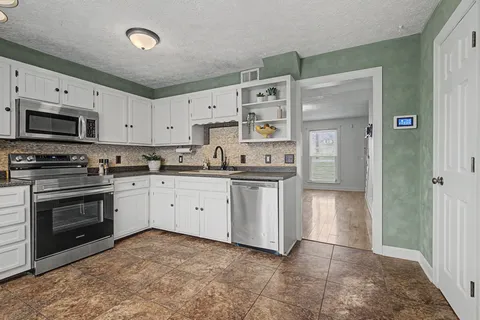 a kitchen with stainless steel appliances granite countertop a stove a sink and a refrigerator