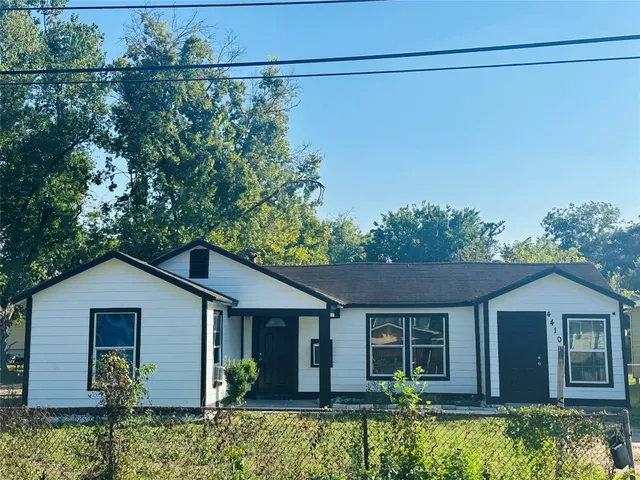 a view of a house with small yard plants and large tree