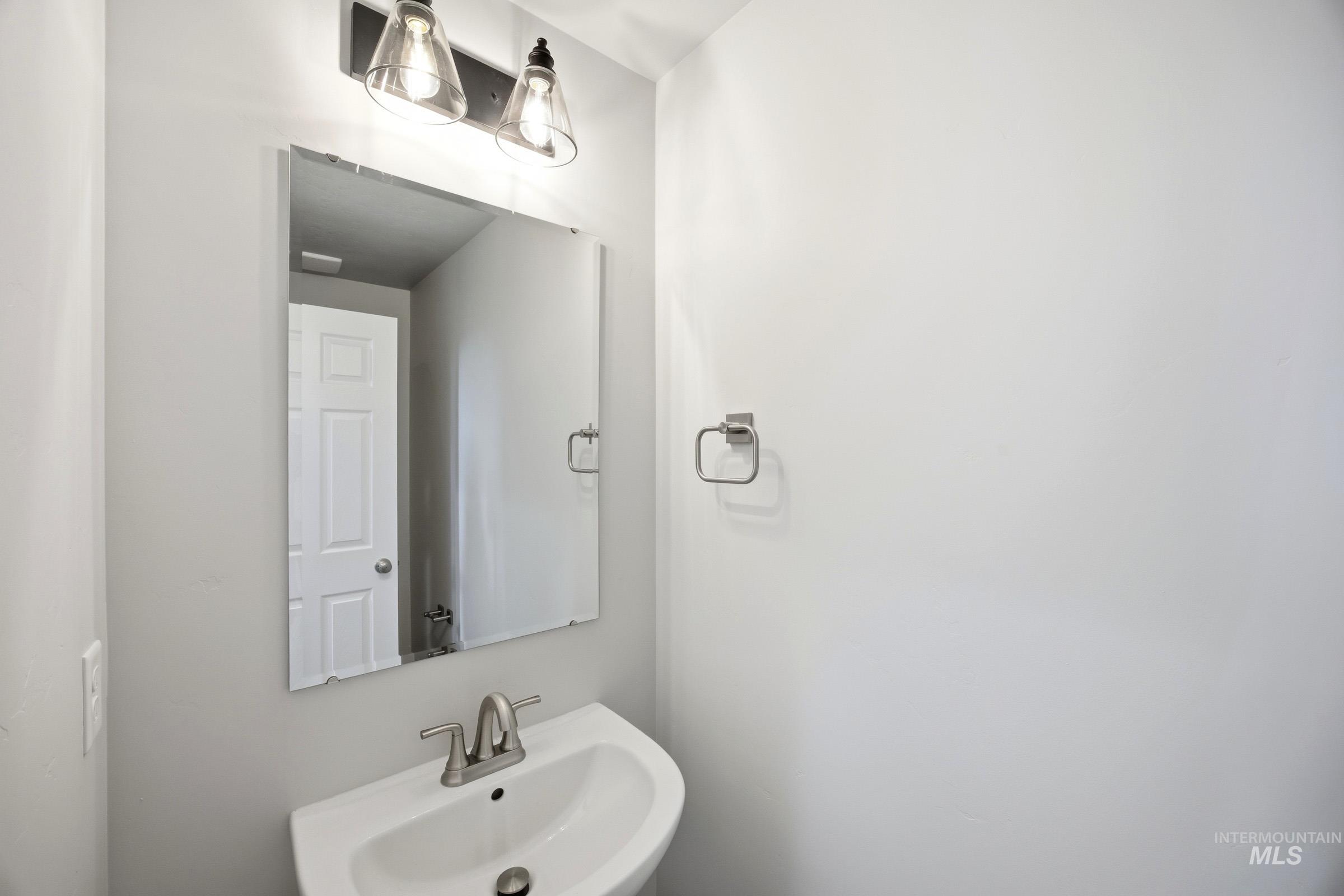 14044 Shiny Spruce Street Caldwell, ID 83607 - Photo 12 of 24 Pedestal sink featuring a brushed nickel faucet and wall-mounted mirror