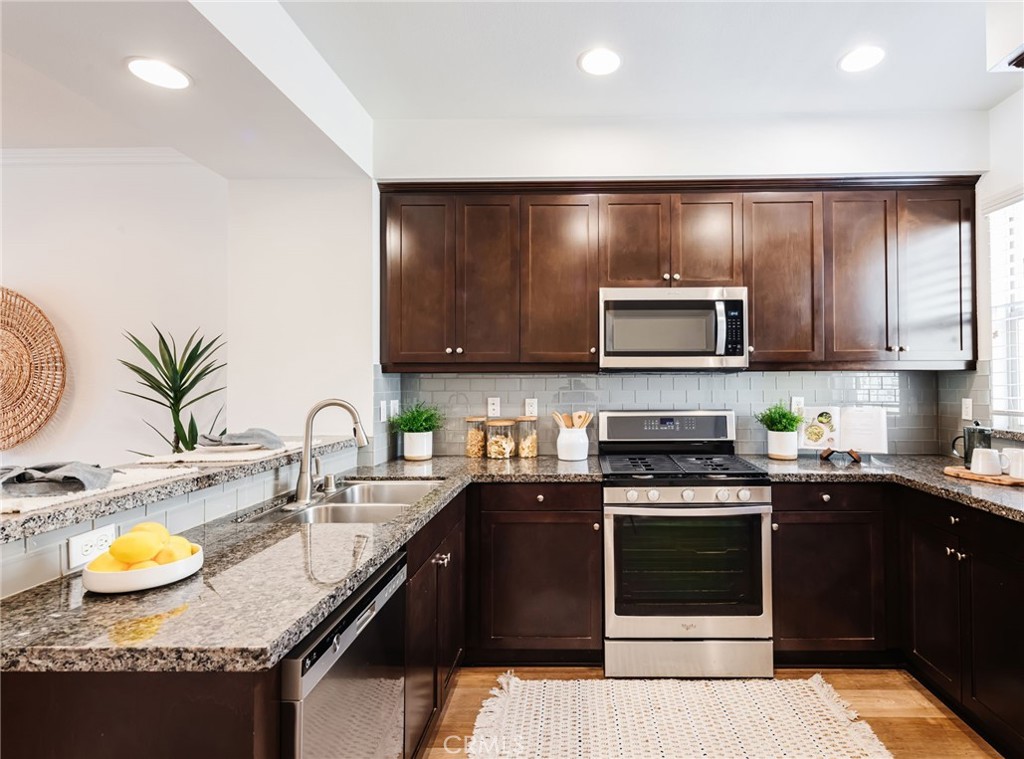 5341 Strand, Unit 105 Hawthorne, CA 90250 - Photo 16 of 67 a kitchen with granite countertop a sink a stove and wooden cabinets