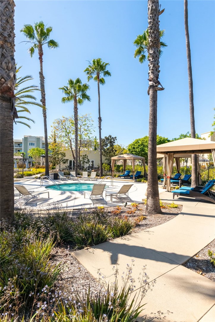 5341 Strand, Unit 105 Hawthorne, CA 90250 - Photo 34 of 67 a view of a swimming pool with a lawn chairs and palm tree