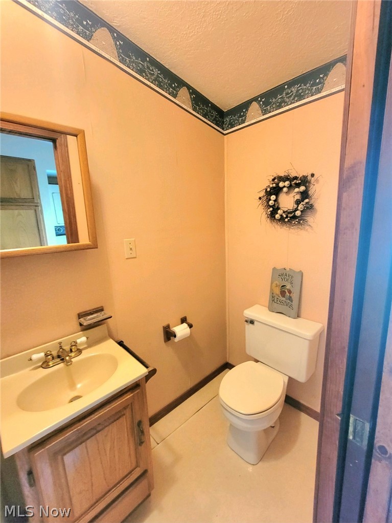 7172 Tessmer Road Williamsfield, OH 44093 - Photo 9 of 23 Bathroom with a textured ceiling, vanity, tile floors, and toilet