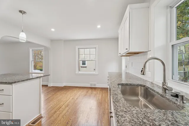 a kitchen with granite countertop a sink a window and cabinets