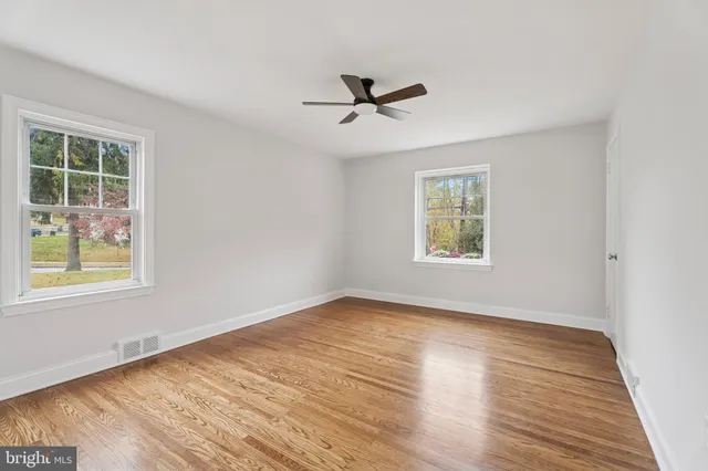 a view of empty room with wooden floor and fan