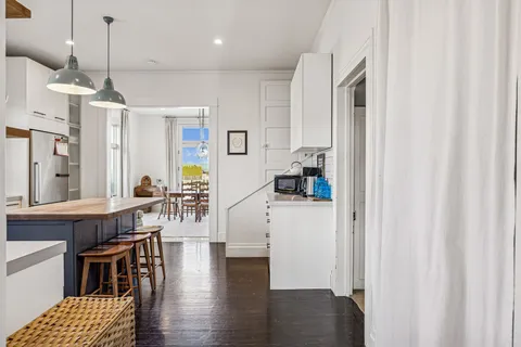 a kitchen with stainless steel appliances granite countertop a refrigerator a sink dishwasher a dining table and chairs with wooden floor