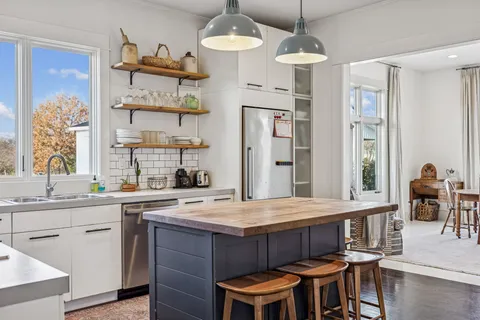 a kitchen with a dining table chairs sink and wooden floor