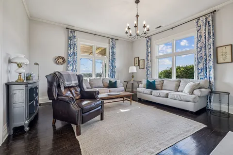 a living room with furniture a chandelier and a large window