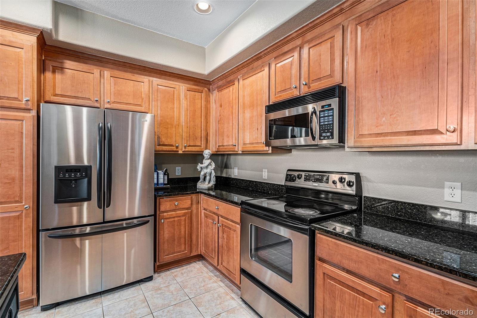 10515 Ashfield Street, Unit 1D Highlands Ranch, CO 80126 - Photo 19 of 39 a kitchen with granite countertop a refrigerator stove top oven and cabinets