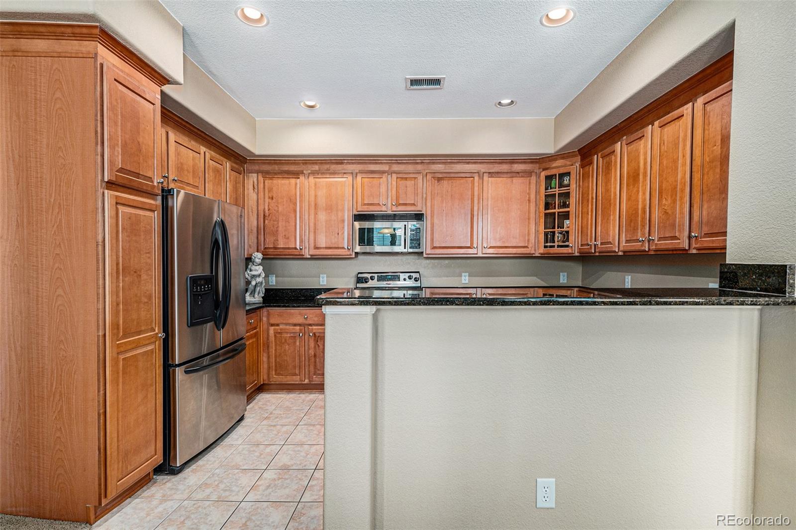 10515 Ashfield Street, Unit 1D Highlands Ranch, CO 80126 - Photo 20 of 39 a kitchen with granite countertop a refrigerator stove top oven and sink