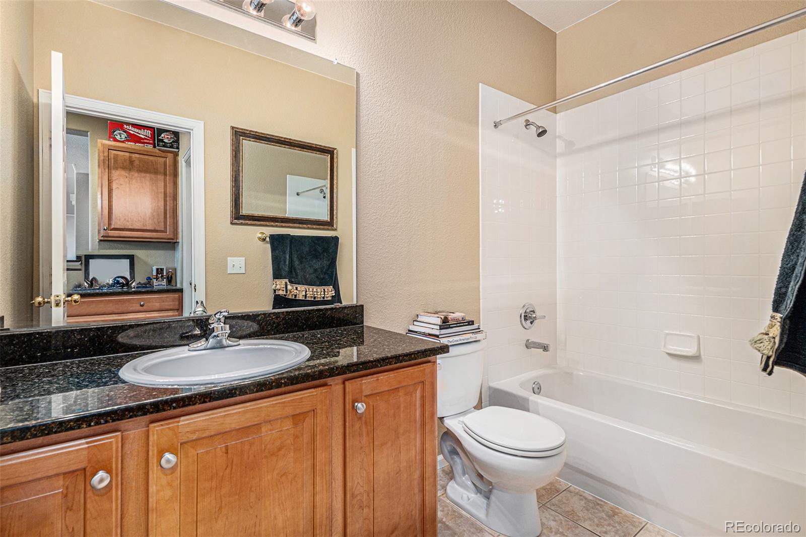 10515 Ashfield Street, Unit 1D Highlands Ranch, CO 80126 - Photo 27 of 39 a bathroom with a granite countertop sink toilet and shower