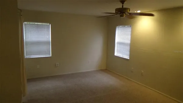 en empty room with a fan and a window