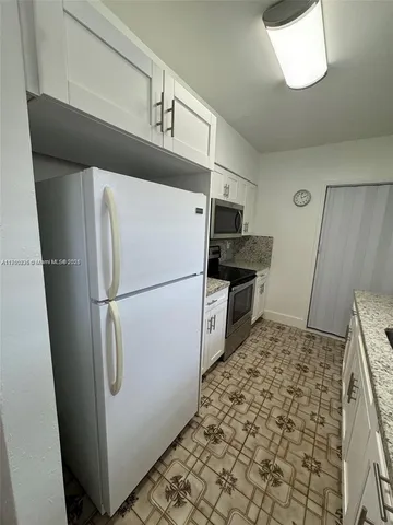 a white refrigerator freezer and a stove sitting inside of a kitchen