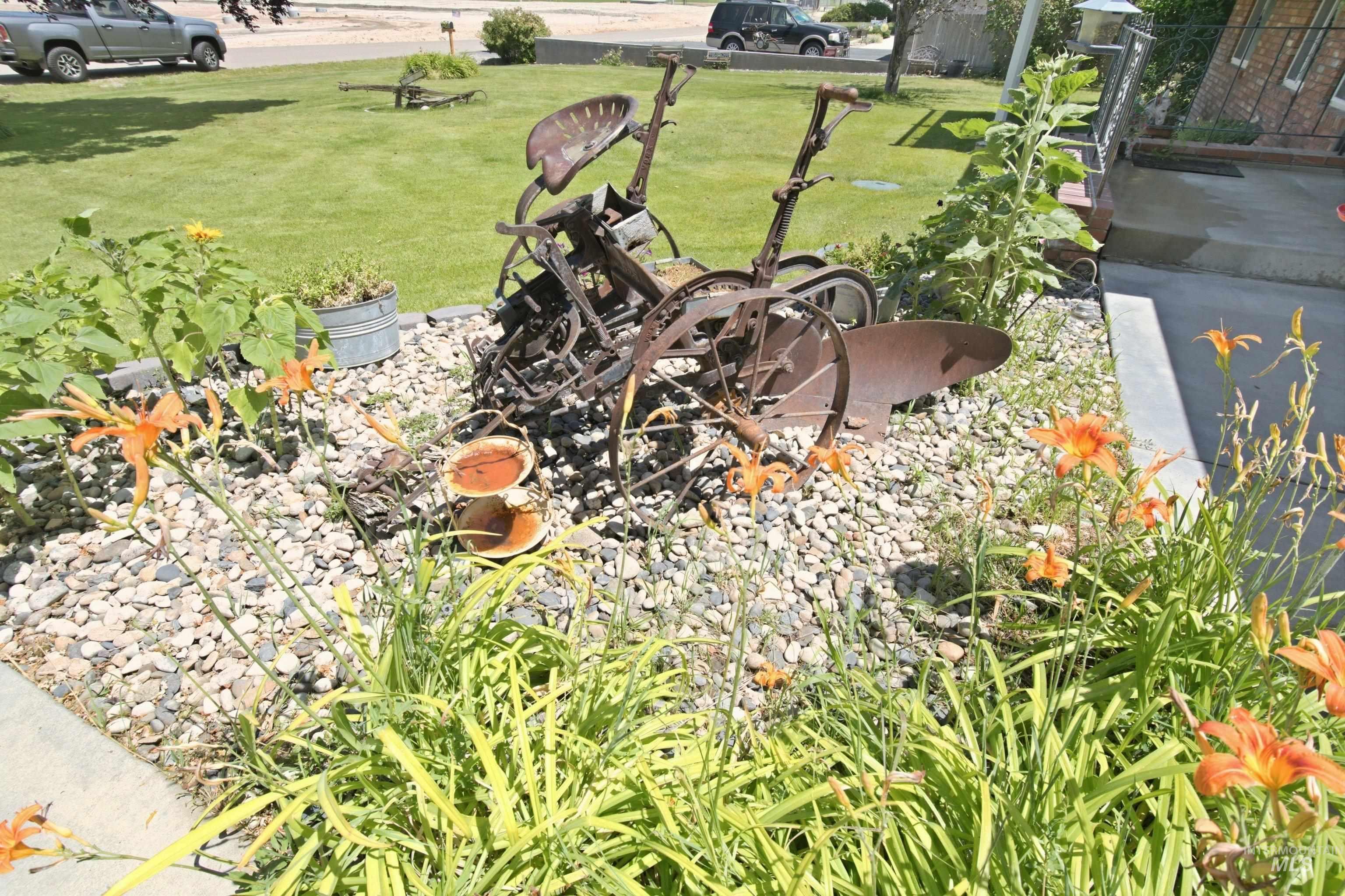 15095 David Street Caldwell, ID 83607 - Photo 6 of 39 Landscaped front yard featuring decorative rock beds, mature green foliage, and vibrant orange daylilies