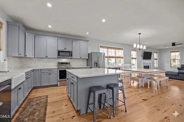 a dining room with wooden floor a chandelier a wooden table and chairs