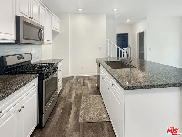 a kitchen with stainless steel appliances granite countertop a stove a sink and a microwave