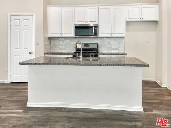 a kitchen with granite countertop a refrigerator and a stove