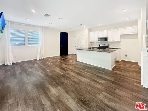 a kitchen with stainless steel appliances kitchen island granite countertop a stove a sink and a refrigerator