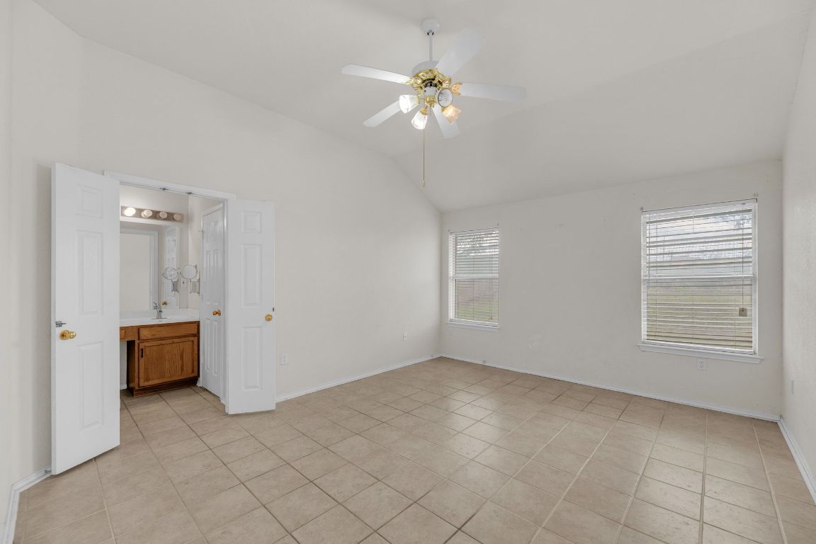 2317 Chestnut Path Round Rock, TX 78664 - Photo 18 of 36 Unfurnished bedroom featuring lofted ceiling, light tile patterned floors, ceiling fan, and connected bathroom