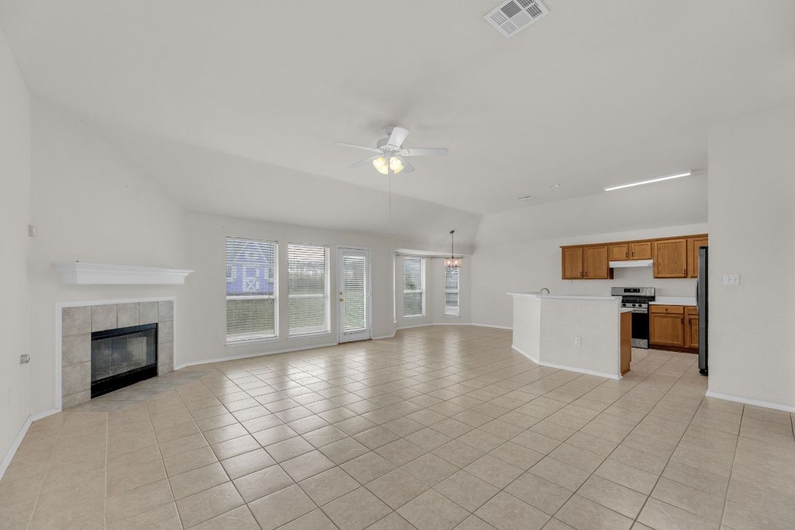 2317 Chestnut Path Round Rock, TX 78664 - Photo 5 of 36 Unfurnished living room featuring light tile patterned floors, ceiling fan, a tile fireplace, and lofted ceiling