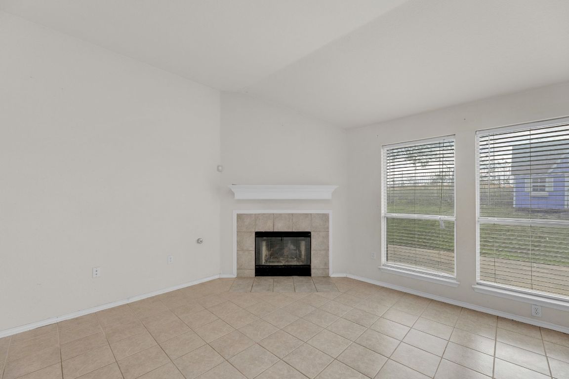 2317 Chestnut Path Round Rock, TX 78664 - Photo 7 of 36 Unfurnished living room with a tiled fireplace and light tile patterned floors