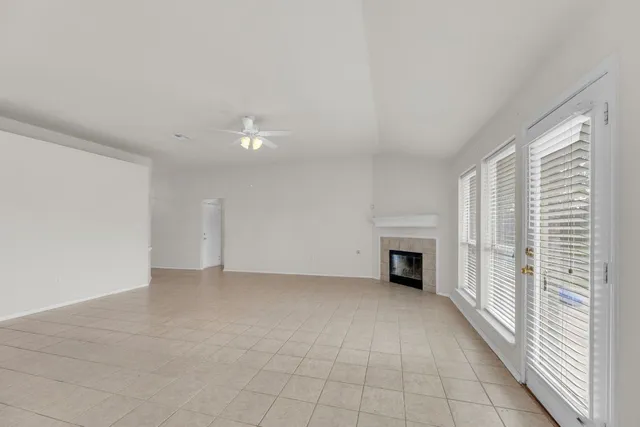 an empty room with windows and fireplace