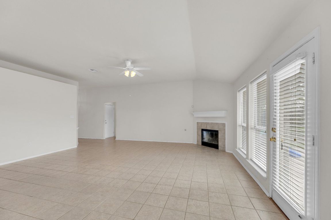 2317 Chestnut Path Round Rock, TX 78664 - Photo 8 of 36 Unfurnished living room with a tiled fireplace, light tile patterned floors, ceiling fan, and lofted ceiling