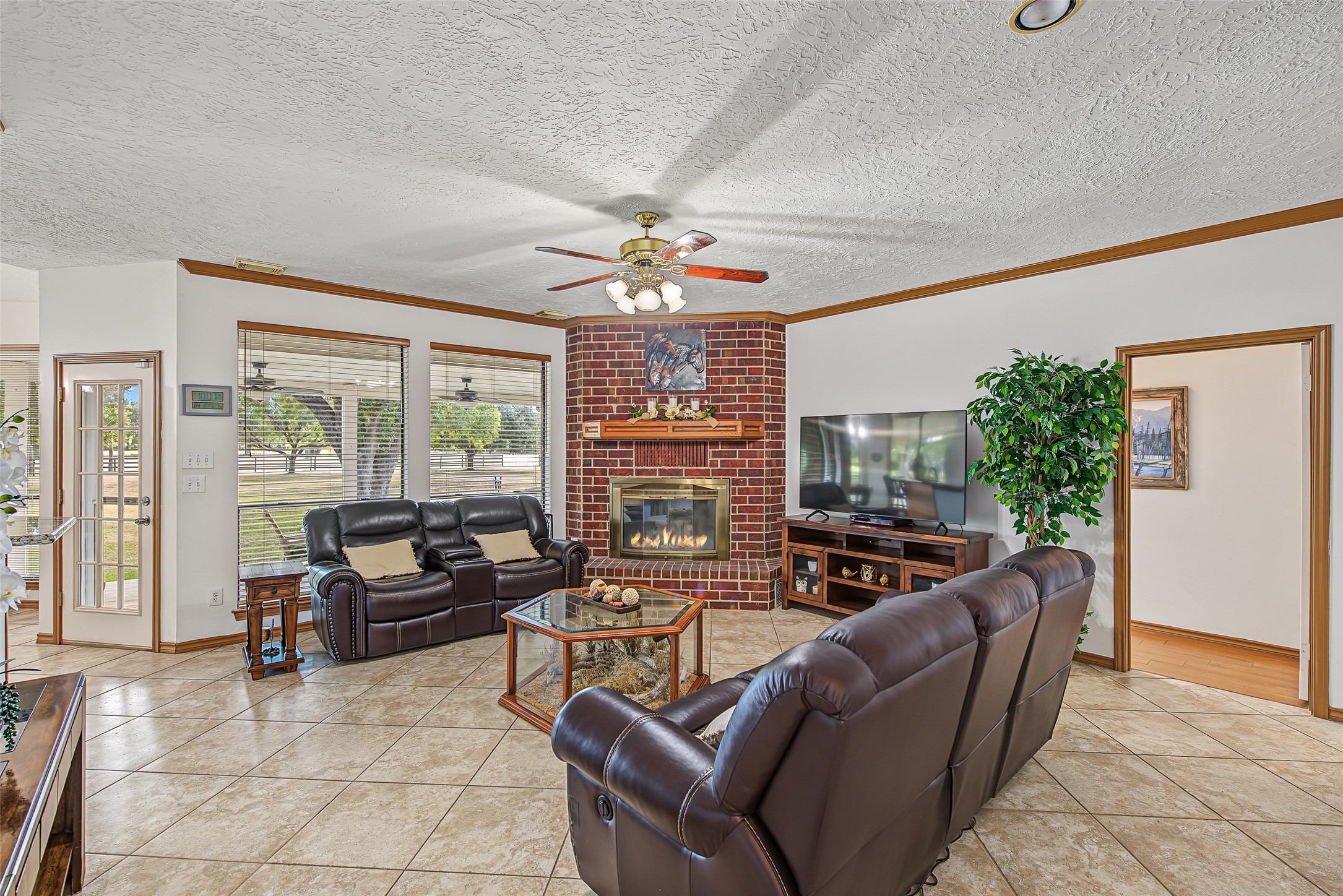 1345 Peach Ridge Road Brookshire, TX 77423 - Photo 16 of 50 This inviting living room serves as the cozy heart of the home, centered around a dramatic floor-to-ceiling red brick fireplace with a wood mantle and built-in glass hearth.
