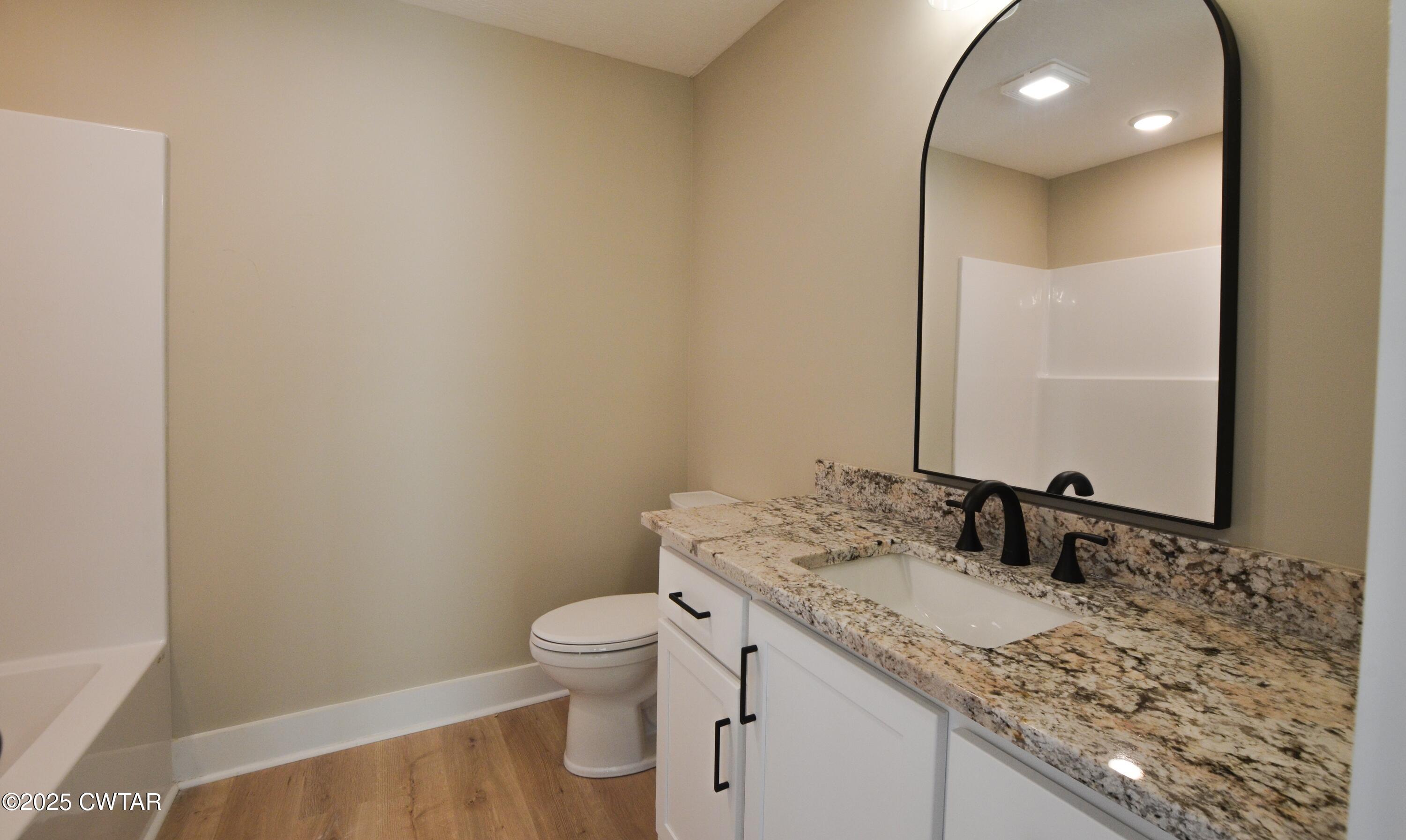 297 Marlow Cemetery Road Gadsden, TN 38337 - Photo 25 of 28 a bathroom with a granite countertop sink a toilet and a mirror