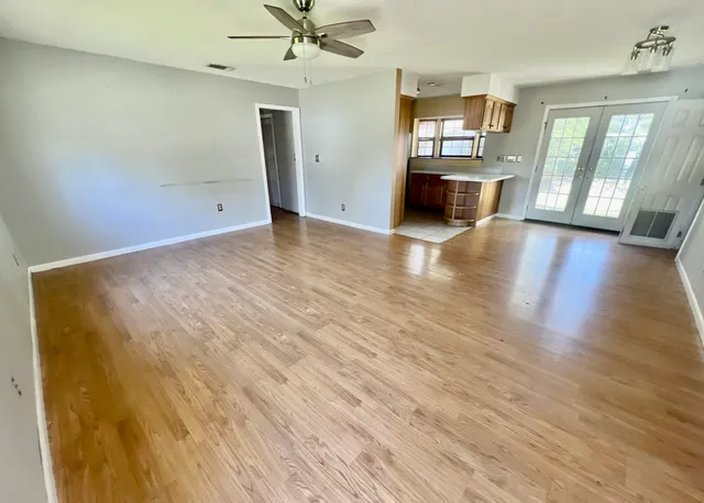 an empty room with wooden floor and windows