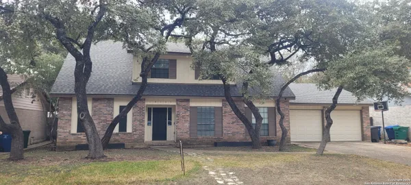 a front view of a house with a tree