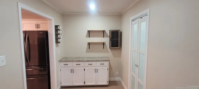 a bathroom with a granite countertop sink and a refrigerator