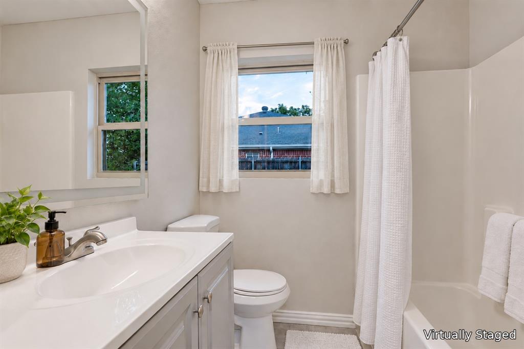 514 Chickapoo Trace Grand Prairie, TX 75051 - Photo 20 of 25 Bathroom featuring a gray vanity with a white countertop, an undermount sink, a toilet, and a bathtub with a shower