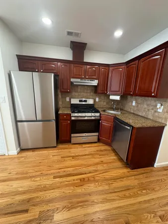a kitchen with granite countertop a refrigerator stove and wooden cabinets