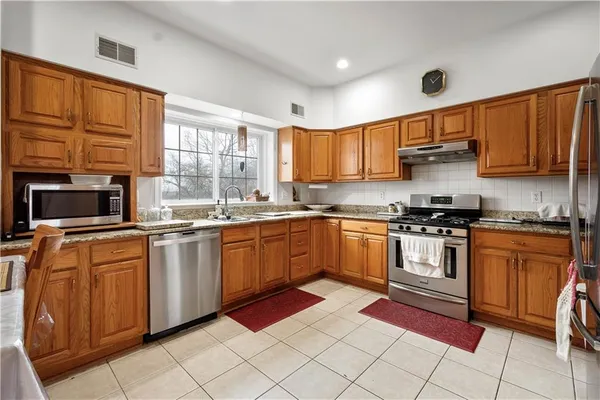 a kitchen with stainless steel appliances granite countertop a stove top oven a sink dishwasher a dining table and chairs with wooden floor