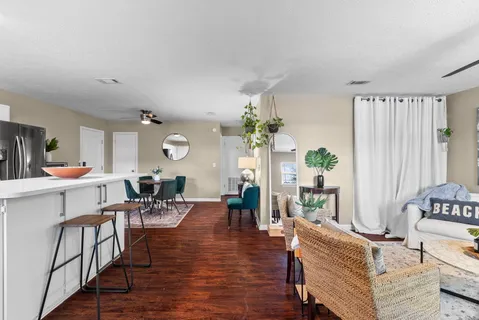 a living room with furniture kitchen view and a wooden floor