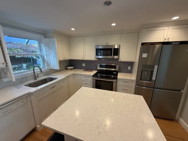 a kitchen with a refrigerator a sink a stove a microwave a counter top space and cabinets