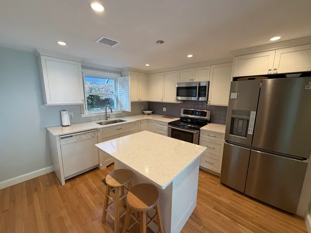 a kitchen with a refrigerator a sink dishwasher and a stove top oven with wooden floor