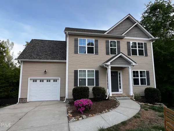 a view of a white house with a yard and large tree