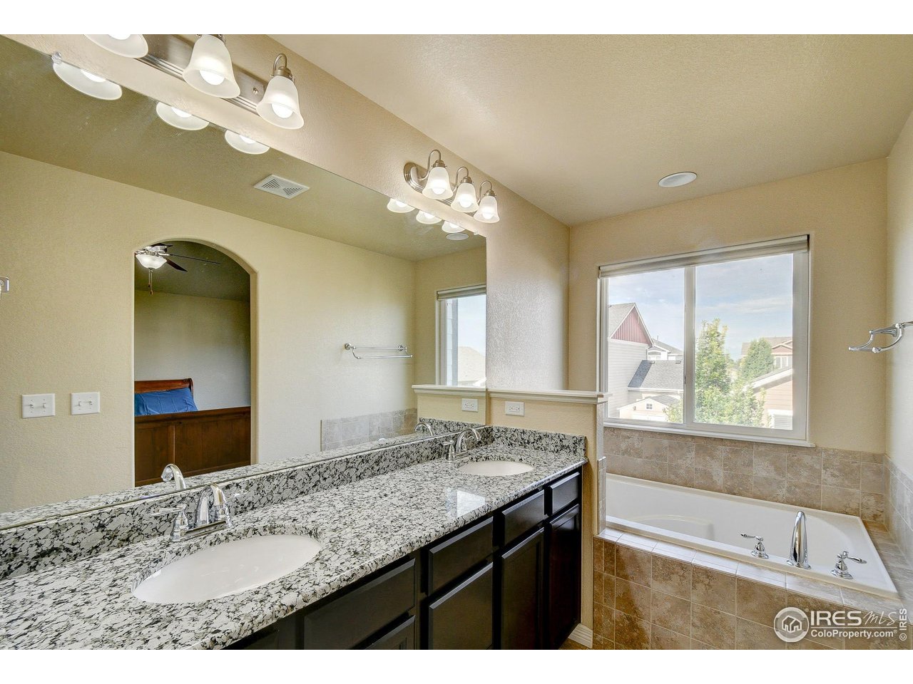 6743 Sequoia Street Frederick, CO 80530 - Photo 14 of 39 a bathroom with a granite countertop sink a large mirror and a bathtub with shower
