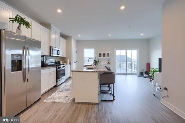 a kitchen with stainless steel appliances a dining table chairs stove refrigerator and cabinets