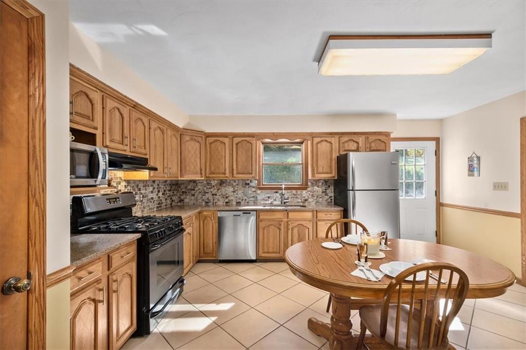 140 Curry Road Burgettstown, PA 15021 - Photo 9 of 25 a kitchen with granite countertop stainless steel appliances a refrigerator a stove a sink dishwasher a dining table and chairs with wooden floor