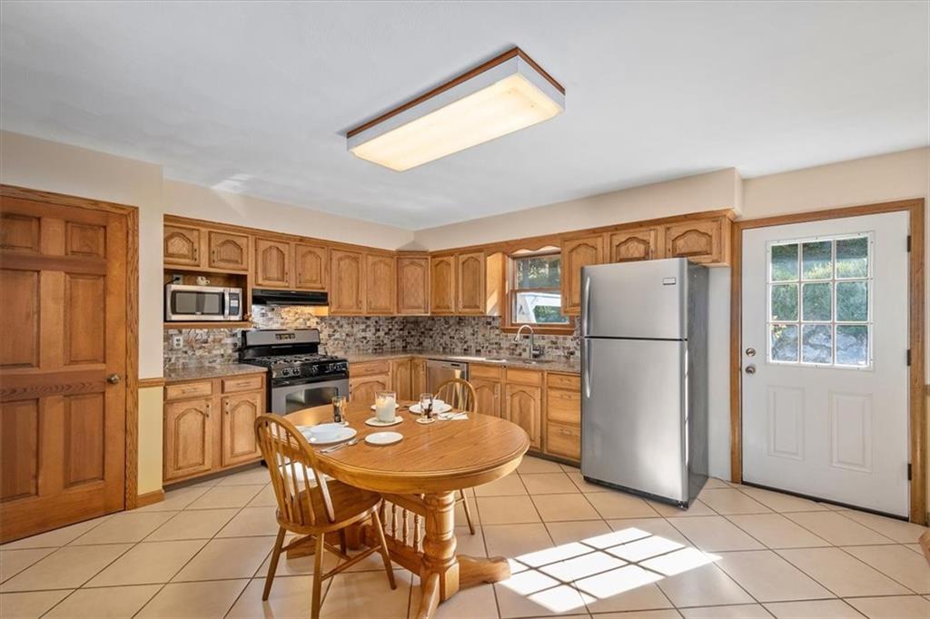 140 Curry Road Burgettstown, PA 15021 - Photo 10 of 25 a kitchen with a refrigerator a stove a dining table and chairs