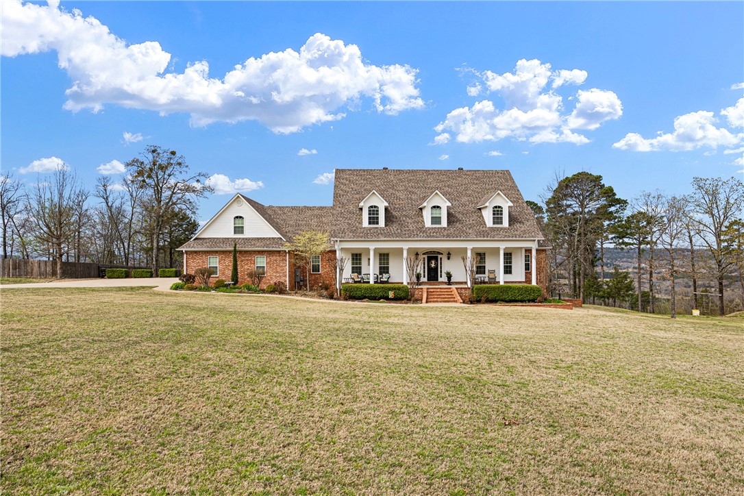 Cape cod house featuring covered porch, a front yard, and brick siding