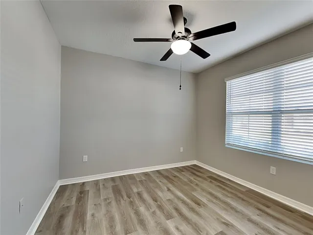 a view of empty room with wooden floor and fan