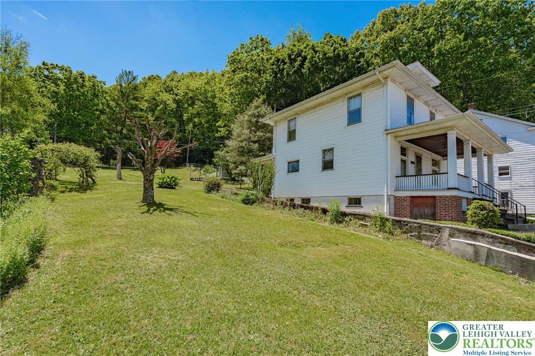 159 West Ridge Street Nesquehoning, PA 18240 - Photo 37 of 55 A classic facade with a covered porch offers hillside living amid lush greenery.