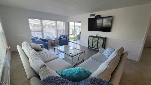 a living room with furniture a flat screen tv and a large window