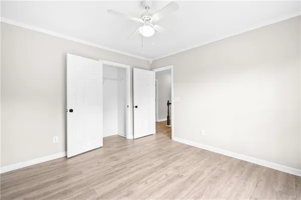 an empty room with wooden floor chandelier fan and windows