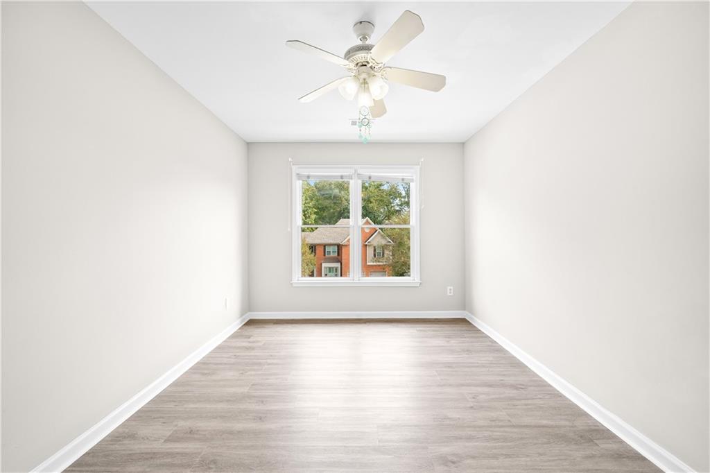 3720 Brookefall Landing Suwanee, GA 30024 - Photo 32 of 41 an empty room with wooden floor chandelier fan and windows