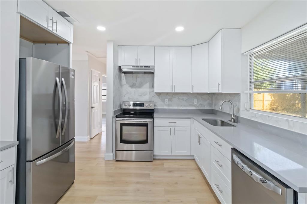 5337 60th Street North Kenneth City, FL 33709 - Photo 9 of 29 a kitchen with stainless steel appliances a refrigerator sink and cabinets