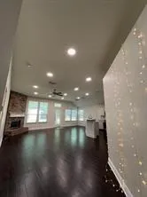 a view of an empty room with wooden floor and a kitchen